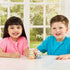 Calico Critters Citrus Bird Family figures feature soft pastel yellow and blue flocked bird dolls in fruit print outfits as smiling children play at table in bright window lit room setting.