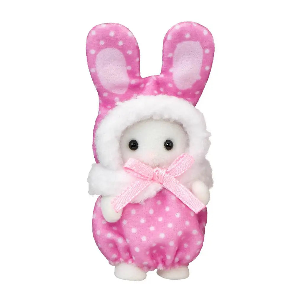Calico Critters baby figure wears a pink polka-dot plush bunny costume with tall pink-lined ears, white fuzzy hood trim, and a pale pink satin bow on a white background.
