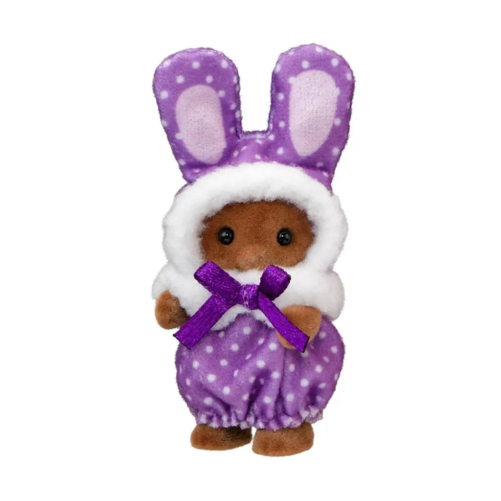 Calico Critters baby figure has brown flocked fur and a purple polka-dot plush bunny costume with tall ears, white fuzzy trim, and a purple bow on a white background.