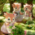 Close-up of Calico Critters Deer Family in a woodland setting, showing the child deer in a pink floral dress near flowers, with parents and baby deer in background.
