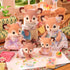 Calico Critters deer family figurines with flocked fur and floral outfits sit in a dollhouse living room while the twin fawns play with paint and toys on the rug.