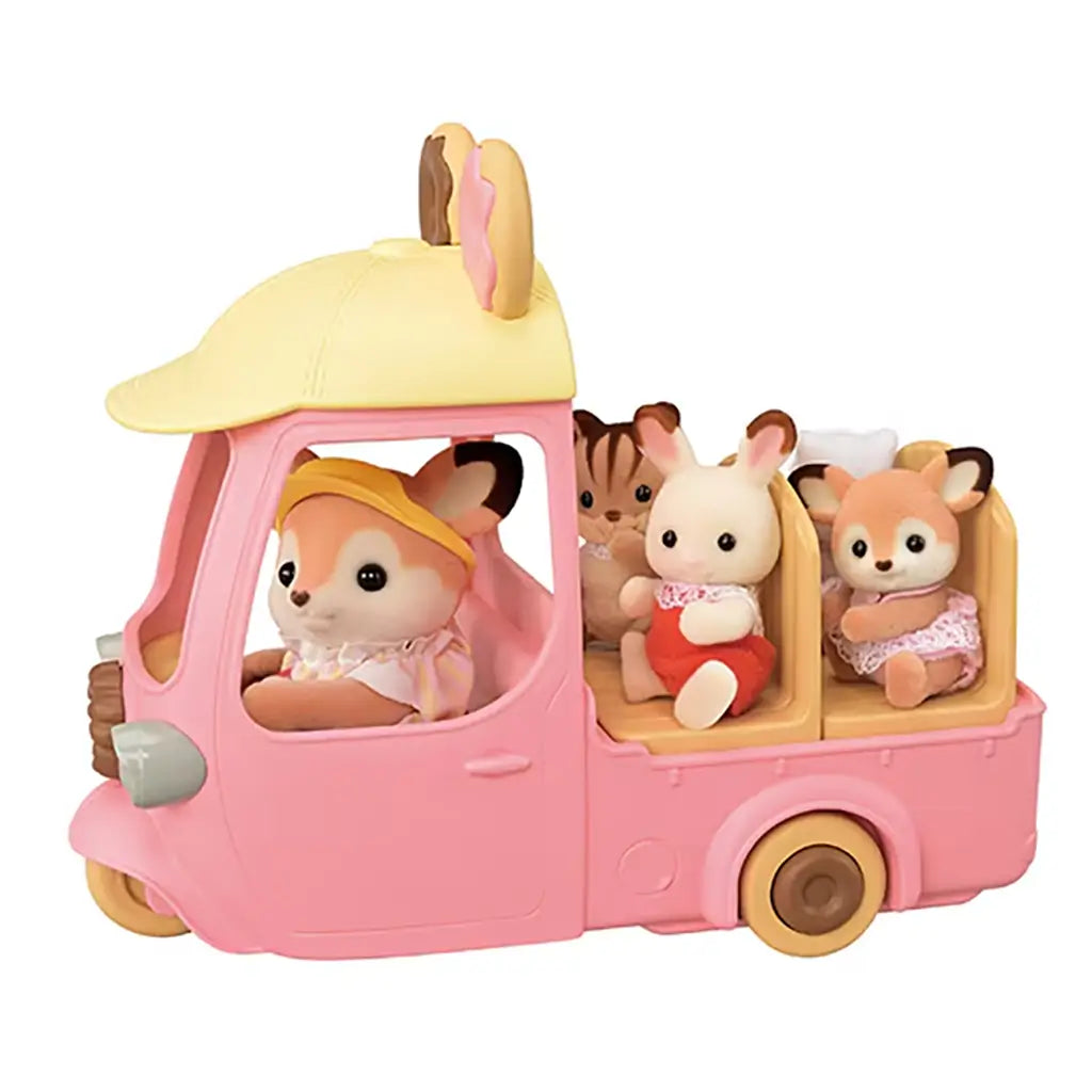 Pink three-wheeled Calico Critters Dip Dip Donuts wagon carries fox driver and three animal passengers including rabbit, kitten, and baby deer, each seated in open back compartments.