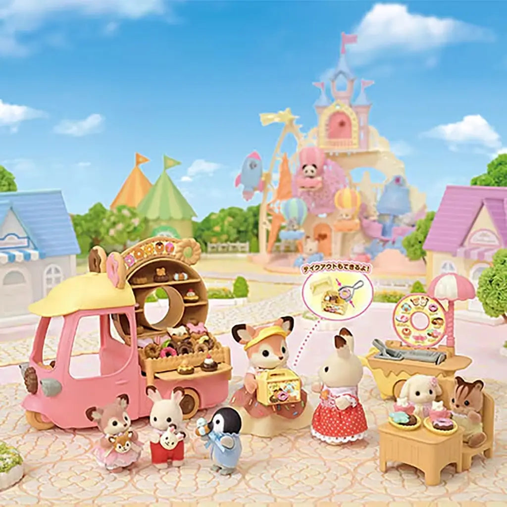 Colorful play scene of Calico Critters Dip Dip Donuts wagon with fox and rabbit figures serving miniature donuts in a pastel village setting featuring toy shops, castle, and balloon rides.