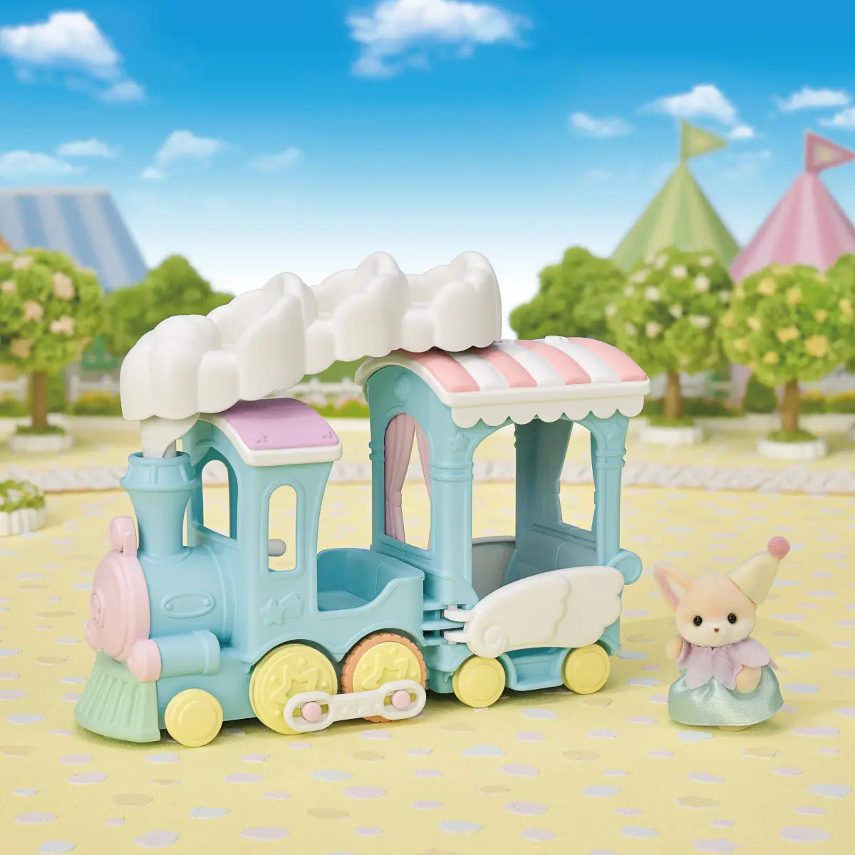 Calico Critters Floating Cloud Rainbow Train playset displays pastel blue plastic locomotive with white cloud canopy, striped roof, and yellow wheels with fox figure in park scene backdrop.