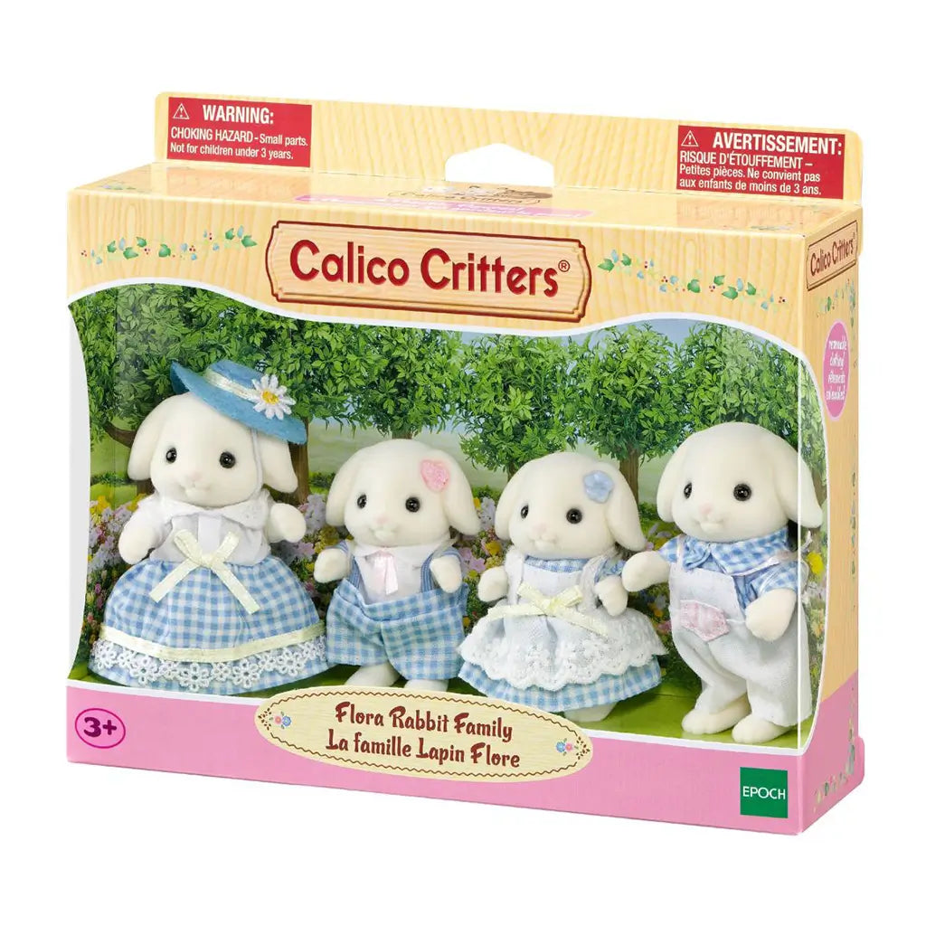 Calico Critters Flora Rabbit Family package displays four cream flocked rabbit figures in blue gingham and pastel outfits inside a windowed box with a garden backdrop.