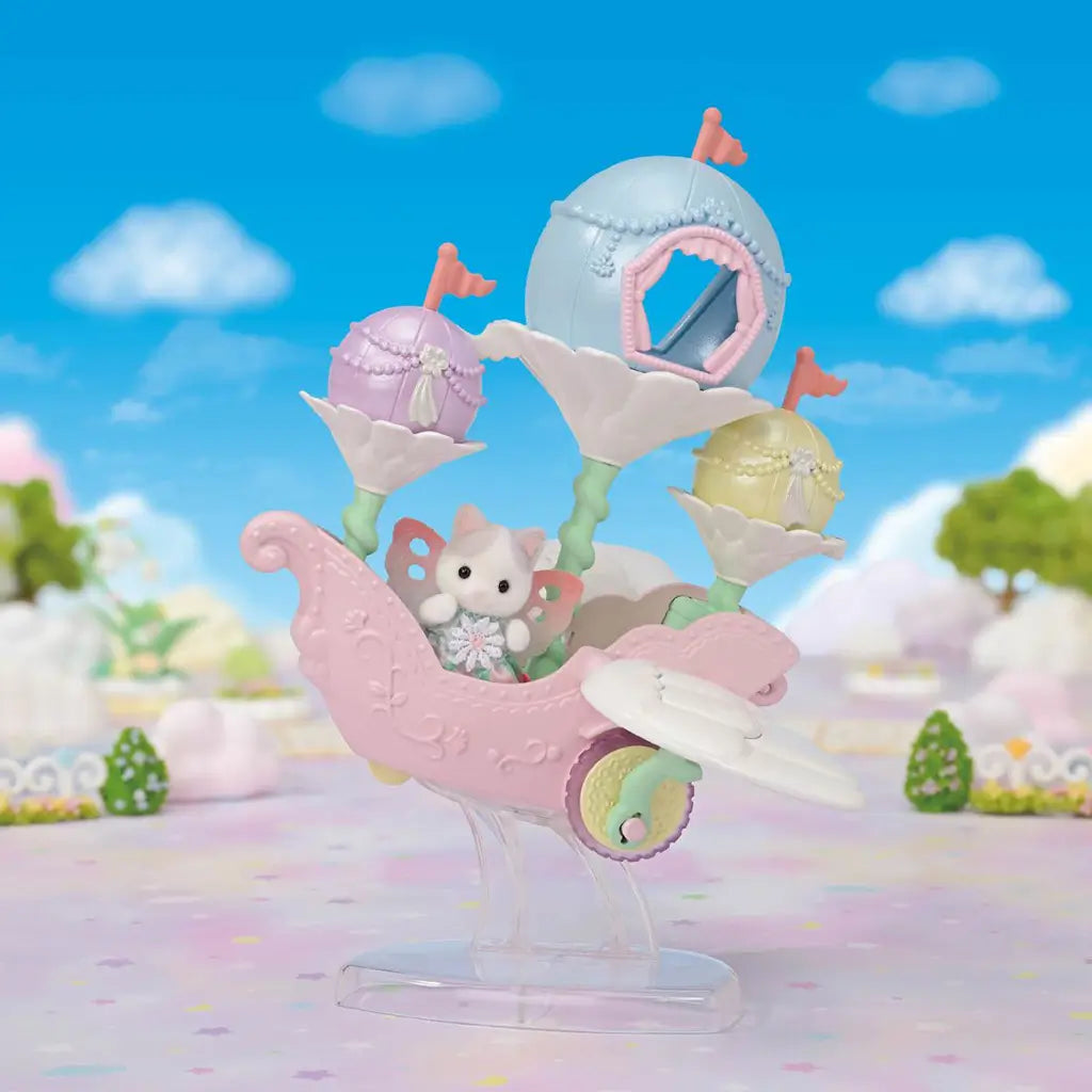 Calico Critters Floral Fantasy Skyship in pastel pink and blue plastic carries a winged Latte Cat baby on a clear stand against a bright fantasy garden and blue sky.
