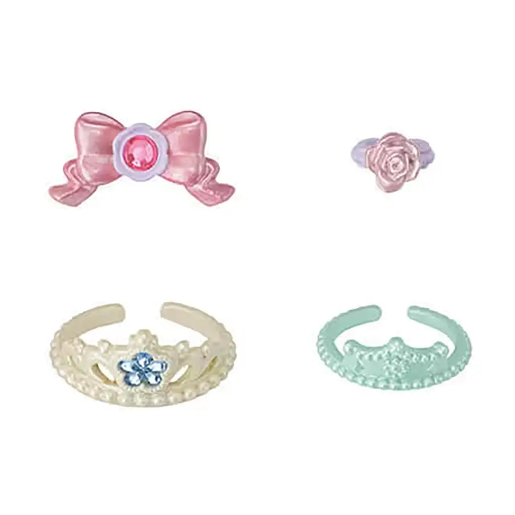 Calico Critters princess accessories include a pink bow, rose-shaped ring, pearl-trimmed tiara, and mint-green crown, each styled with jewel-like details.