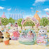 Calico Critters toy figures dressed in pastel princess gowns and tiaras are arranged on a floral stage under a sunny sky with carnival tents and trees in the background.