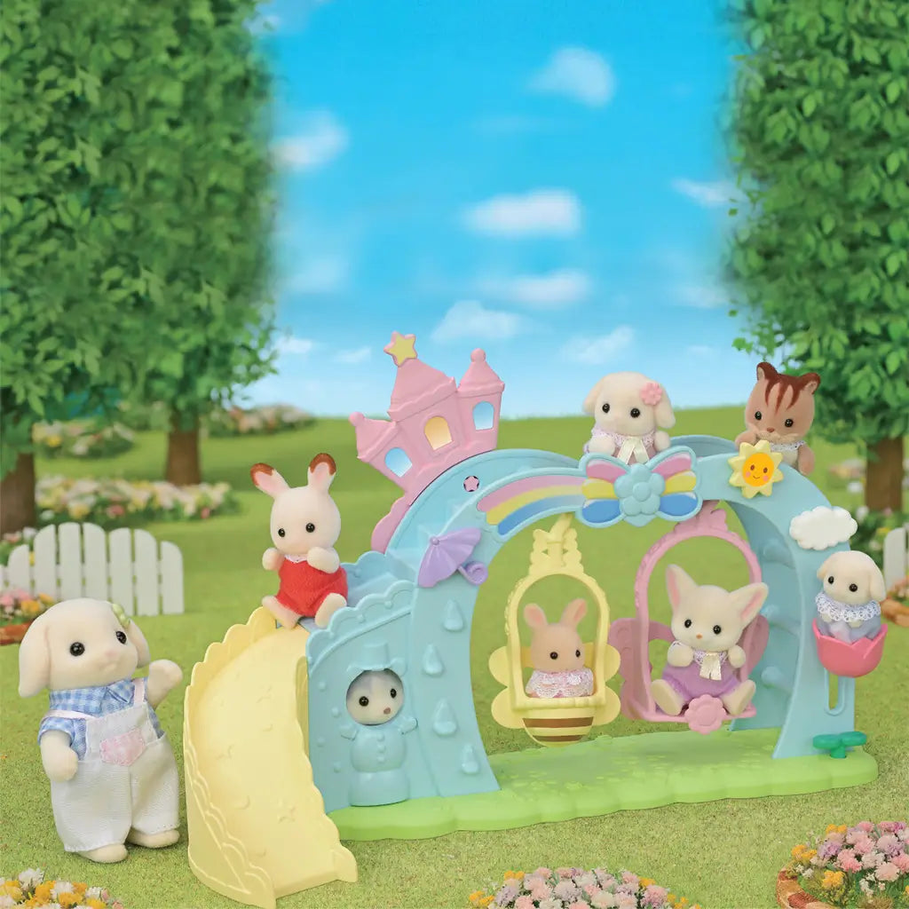 Calico Critters baby figures play on pastel Nursery Swing set with yellow slide, butterfly and bee swings, rainbow arch, and castle accents in grassy outdoor scene.
