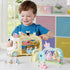 Smiling child in blue shirt plays indoors with Calico Critters Nursery Swing and nursery bus, arranging miniature animal figures on pastel play structures.