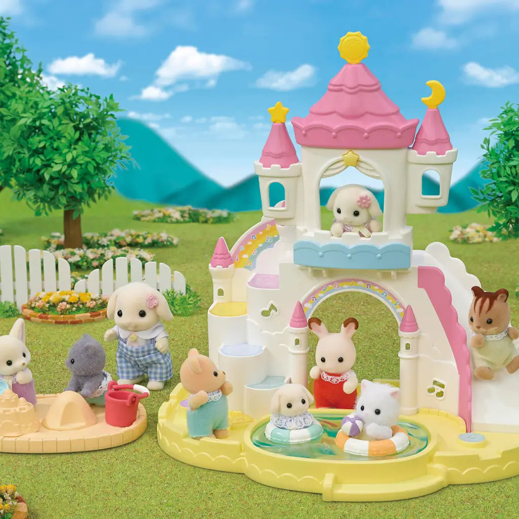 Calico Critters Nursery Sandbox & Pool playset outdoors showing pastel castle structure with slides, a pool, sandbox, and baby animal figures playing with water and sand toys.