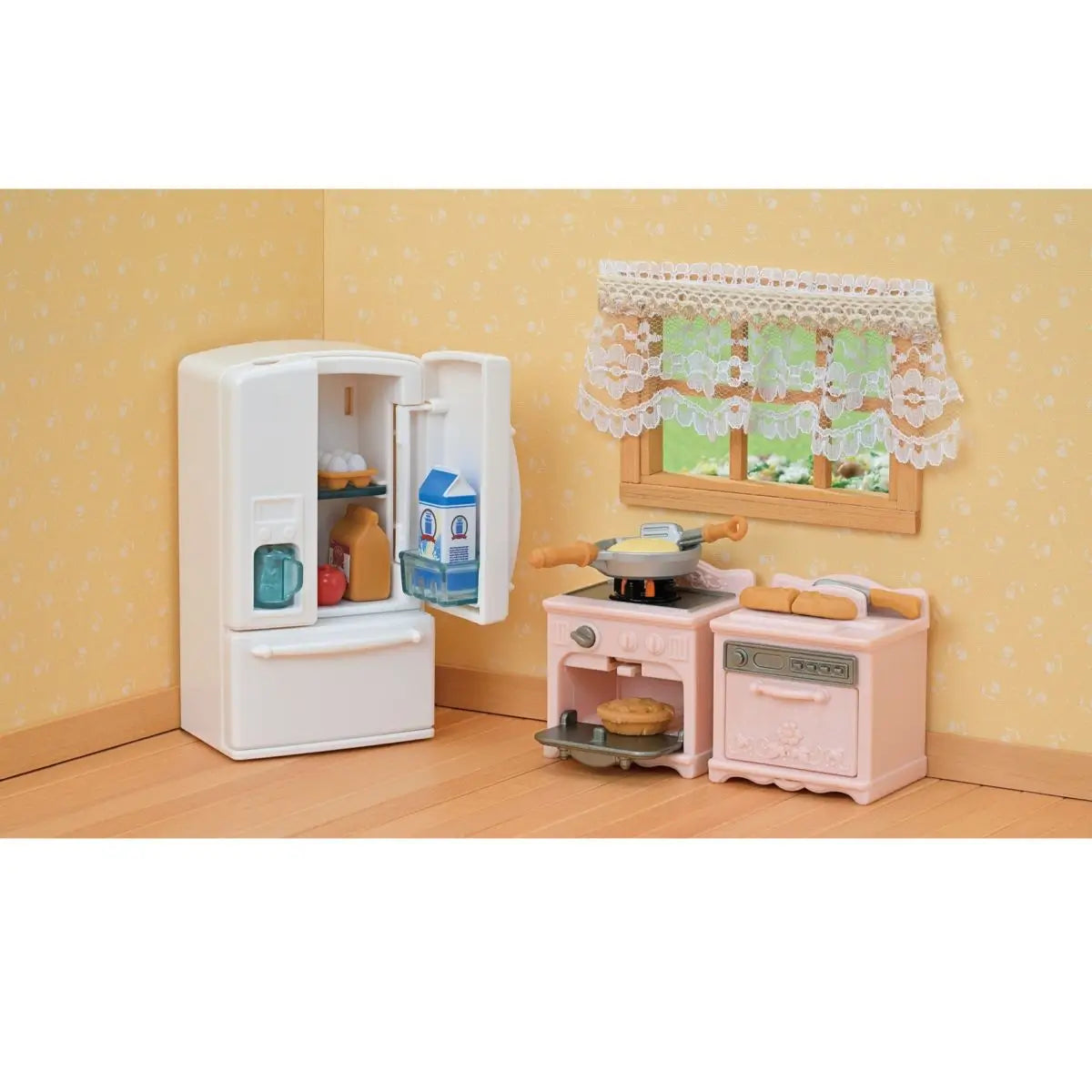 Calico Critters kitchen display features white fridge with aqua cup, pink stove and oven with pan, bread loaves, and lace window curtains styled in yellow dollhouse setting.