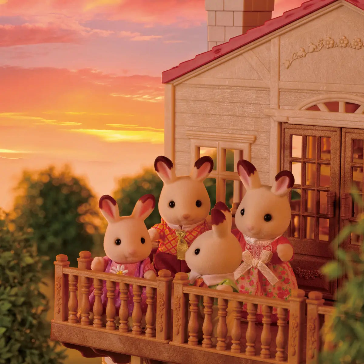 Calico Critters Red Roof Country Home characters include cream flocked rabbit figures wearing colorful dresses and vests posed together on balcony at sunset backdrop.