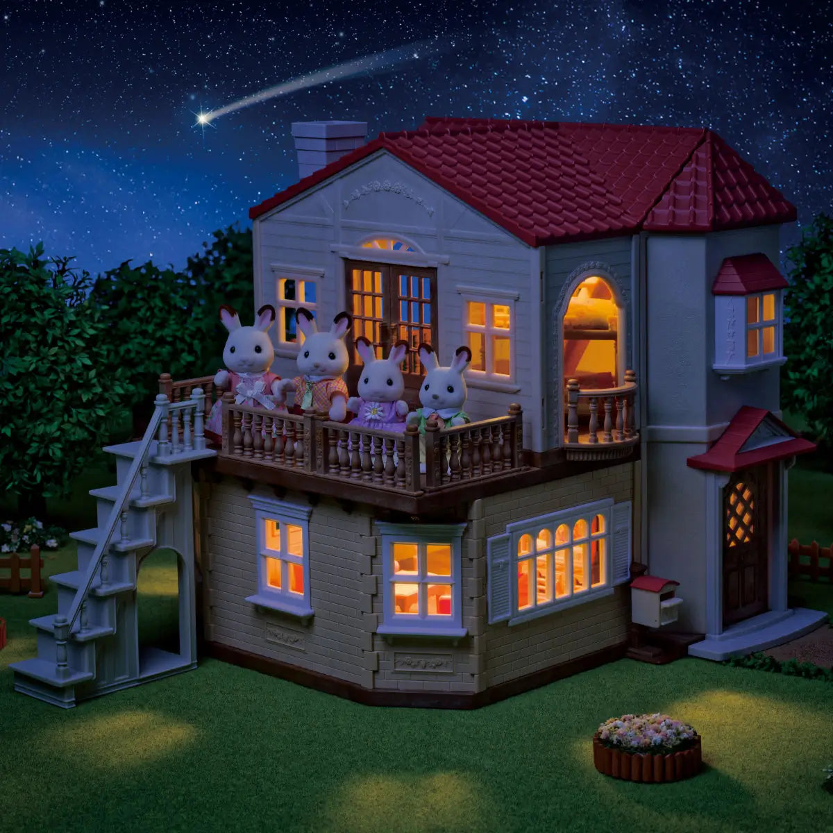 Calico Critters Red Roof Country Home nighttime display features beige dollhouse with glowing windows, red roof tiles, balcony railing, and rabbit figures under starry sky.