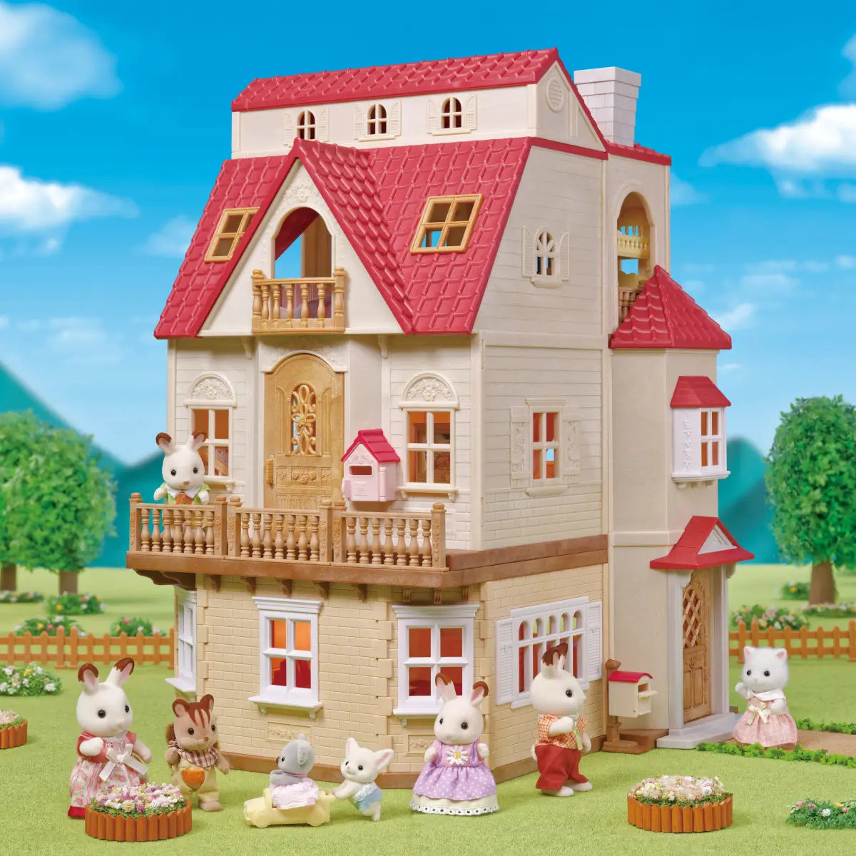 Calico Critters Red Roof Country Home playset displayed outdoors features beige dollhouse with red roof, fenced yard, green trees, and multiple animal figures in garden setting.