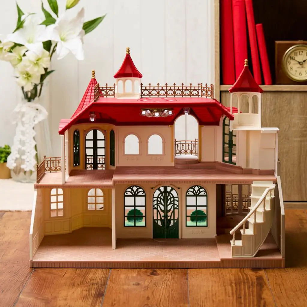 Calico Critters Red Roof Riverside Manor interior shows cream molded rooms, red roof sections, dark green arched doors, bronze railings, staircase, and ceiling lights.