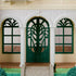 Calico Critters Red Roof Riverside Manor entrance has dark green arched double doors and windows, white molded columns, floral trim, stone path, and green lawn.