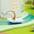 Calico Critters Riverside Manor boat is white and navy plastic with a curved brown fishing rod and blue fish, floating on a turquoise river beside the white mansion.