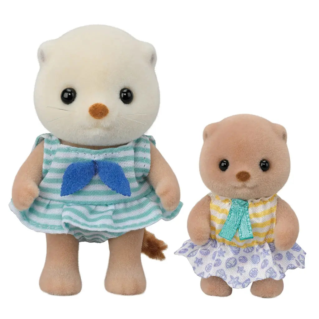 Calico Critters Sea Otter Sisters dolls posed together on a plain white background, both wearing striped and patterned dresses with bows, highlighting detailed flocked fur and outfits.