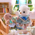 Calico Critters Sea Otter Sisters sitting on a patterned wooden sofa in a cozy living room, with the older sister reading a book to the baby under bright daylight through the window.