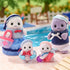 Calico Critters Seal Family toys arranged by a swimming pool scene, including mother, father, and two baby seals dressed in blue and pink, with basket, tote, and float ring.