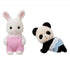 Close-up of Calico Critters snow rabbit baby in pink romper and panda baby in blue diaper with lace trim, both flocked miniature animal figures designed for dollhouse pretend play.