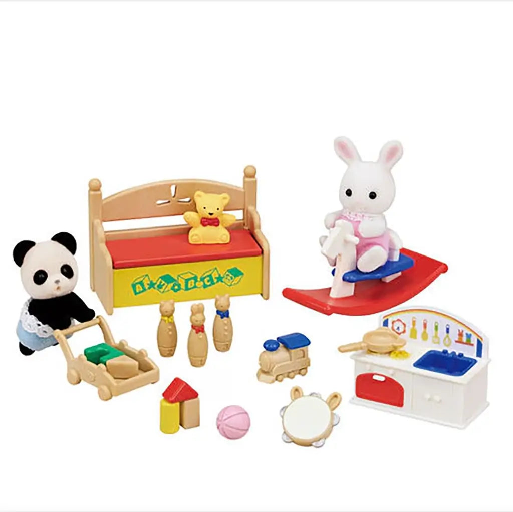 Playset scene with Calico Critters snow rabbit and panda babies surrounded by a toy bench, rocking horse, toy kitchen, bowling pins, train, and small blocks for imaginative play.