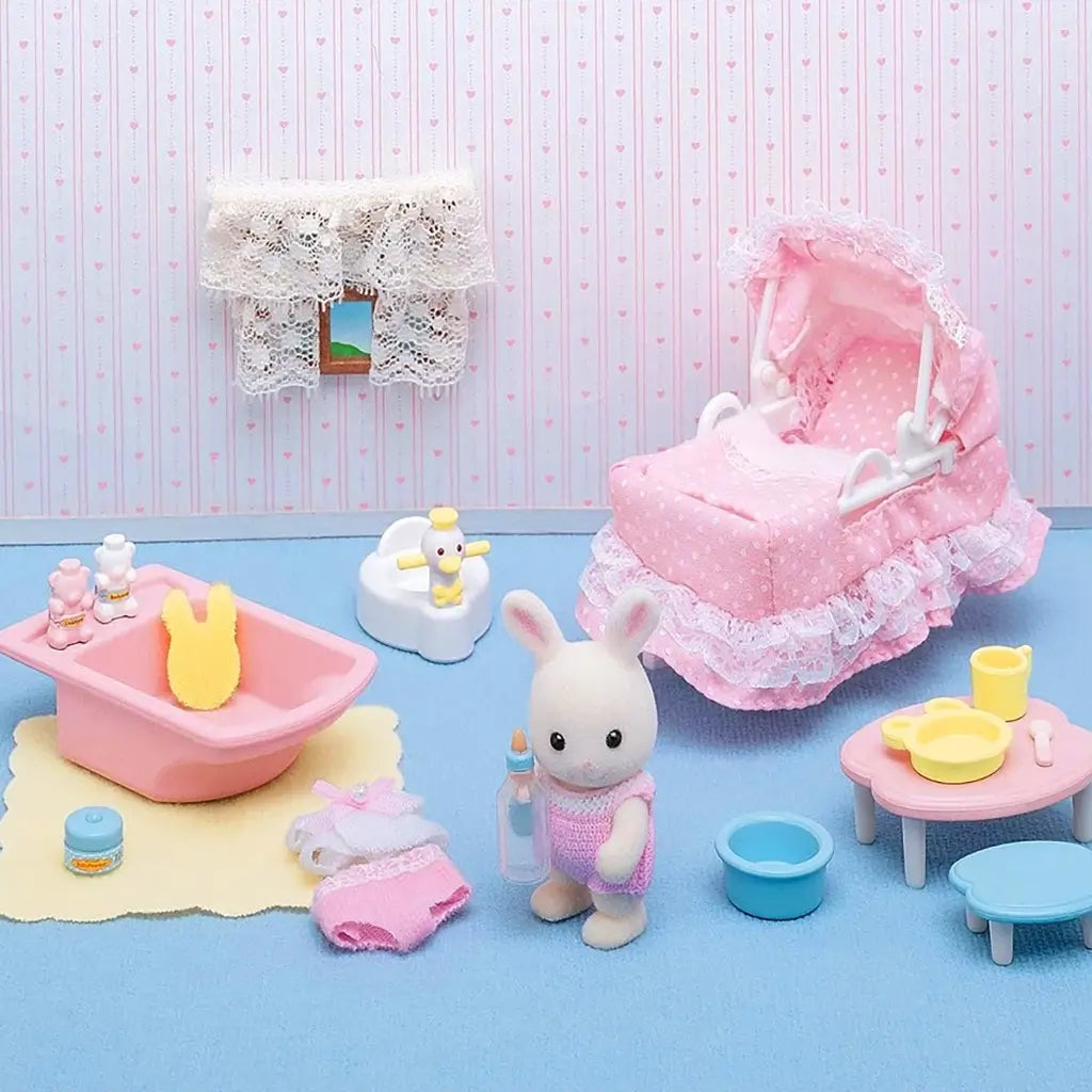 Calico Critters Sophie’s Love ’n Care set features baby rabbit figurine with pink stroller, toy bathtub, potty, feeding table, bottles, and accessories in a dollhouse nursery scene.