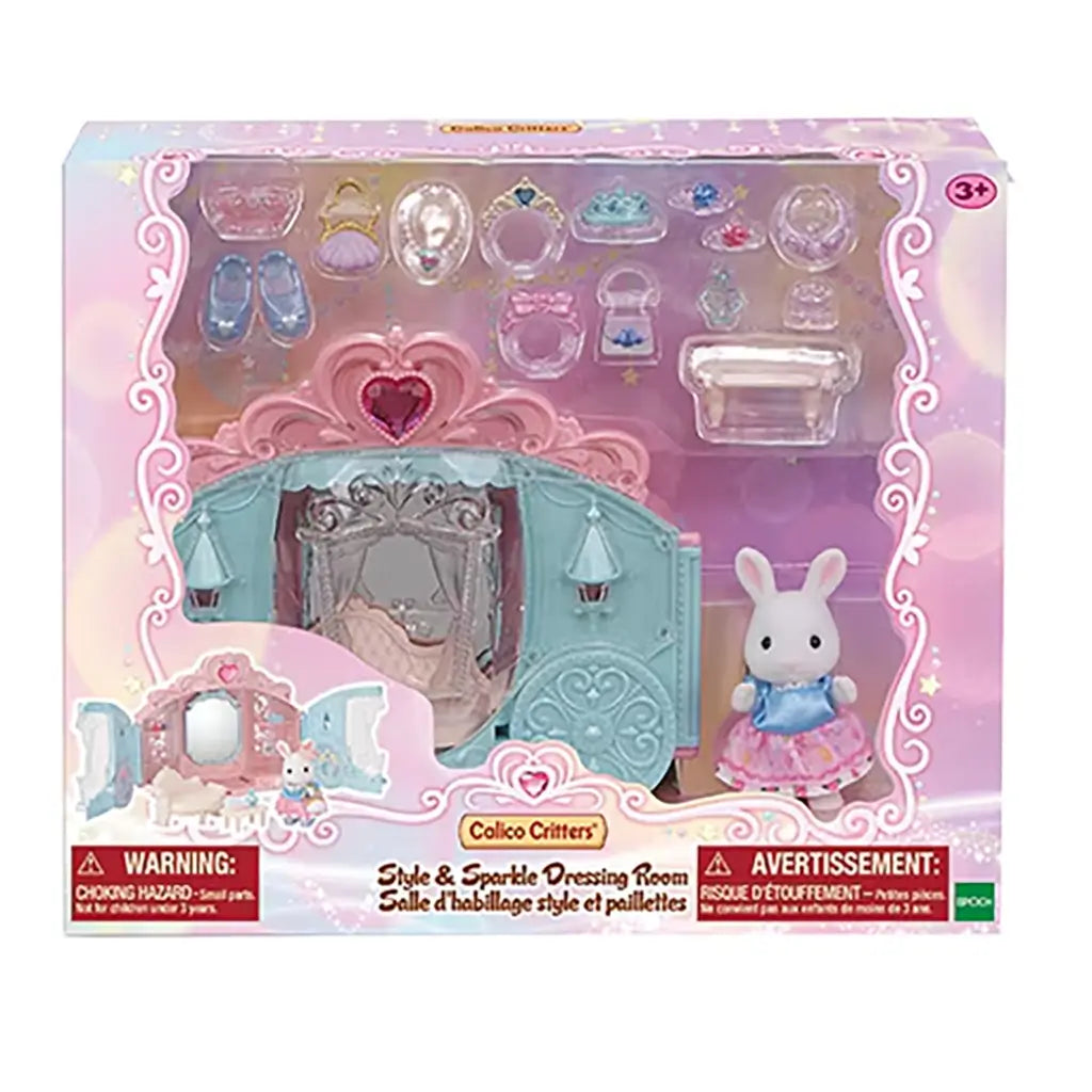 Retail box of Calico Critters Style & Sparkle Dressing Room showing carriage case, rabbit doll, sofa, vanity accessories, tiaras, handbags, and tiny shoes in clear packaging.