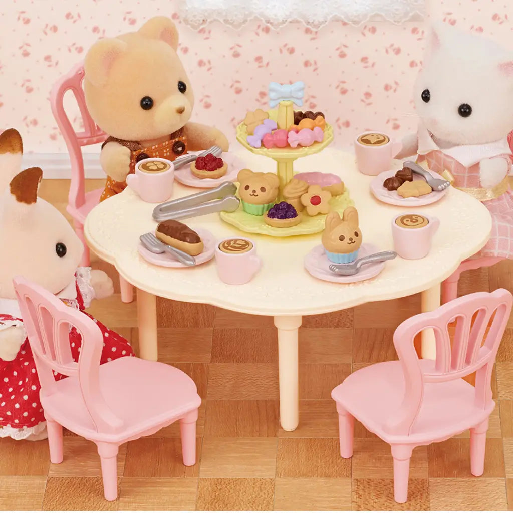 Calico Critters Sweets Party Set with bear, rabbit, and cat figures seated at round table, enjoying cupcakes, pastries, and lattes on pastel plates in a cozy room scene.