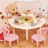 Calico Critters Sweets Party Set with bear, rabbit, and cat figures seated at round table, enjoying cupcakes, pastries, and lattes on pastel plates in a cozy room scene.