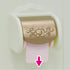 Close-up of Calico Critters Toilet Set toilet paper holder with gold ornate cover, showing pink paper roll being pulled down with arrow indicator.