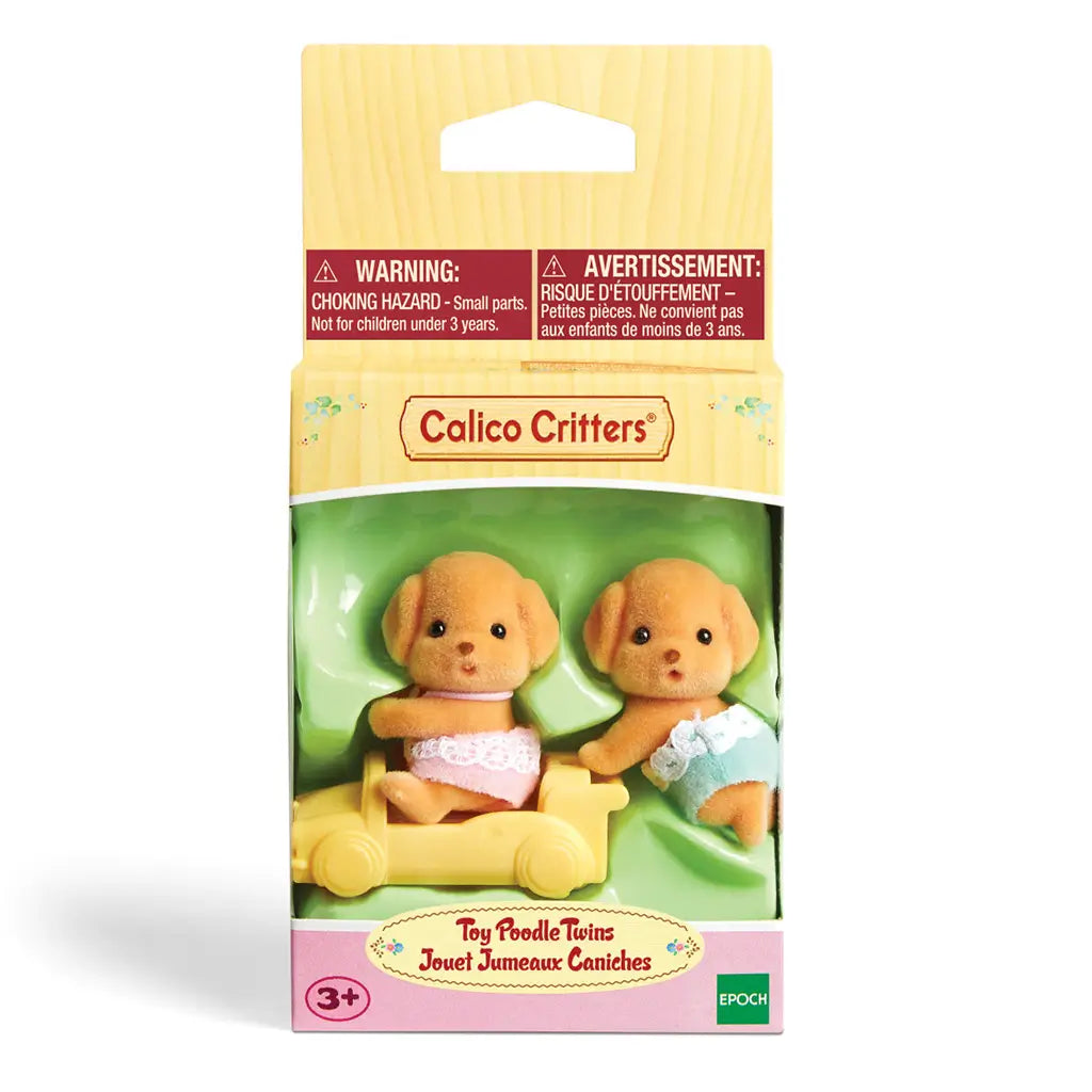 Calico Critters Toy Poodle Twins package shows two brown puppy figurines in diapers, one seated in a yellow toy car and the other standing, inside clear packaging with branding.