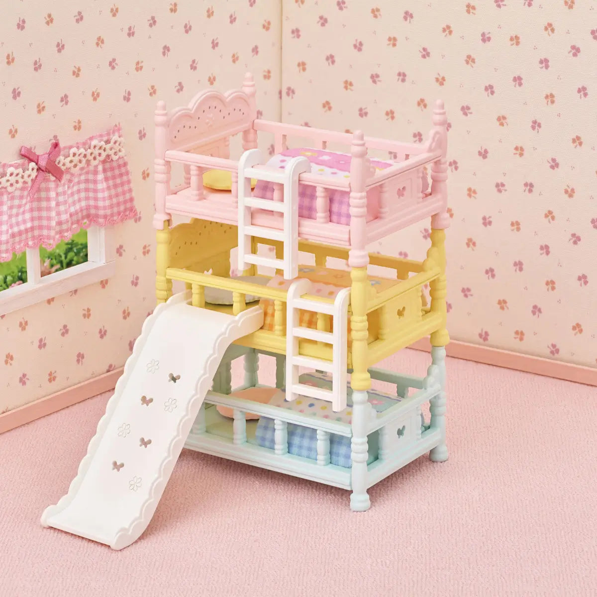 Calico Critters triple bunk beds dollhouse furniture in pastel pink, yellow, and blue plastic with carved details, white ladders, slide, and patterned quilts displayed in miniature bedroom setting.