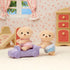 Calico Critters Yellow Labrador twins, Shiloh in pink lace and Marley in blue lace, playing in a pastel dollhouse room with toy car, dresser, curtains, and slide backdrop.