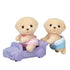 Calico Critters Yellow Labrador twin figurines with soft beige fur, one in a pink lace outfit sitting in a lavender toy car and the other in blue lace outfit pushing it.