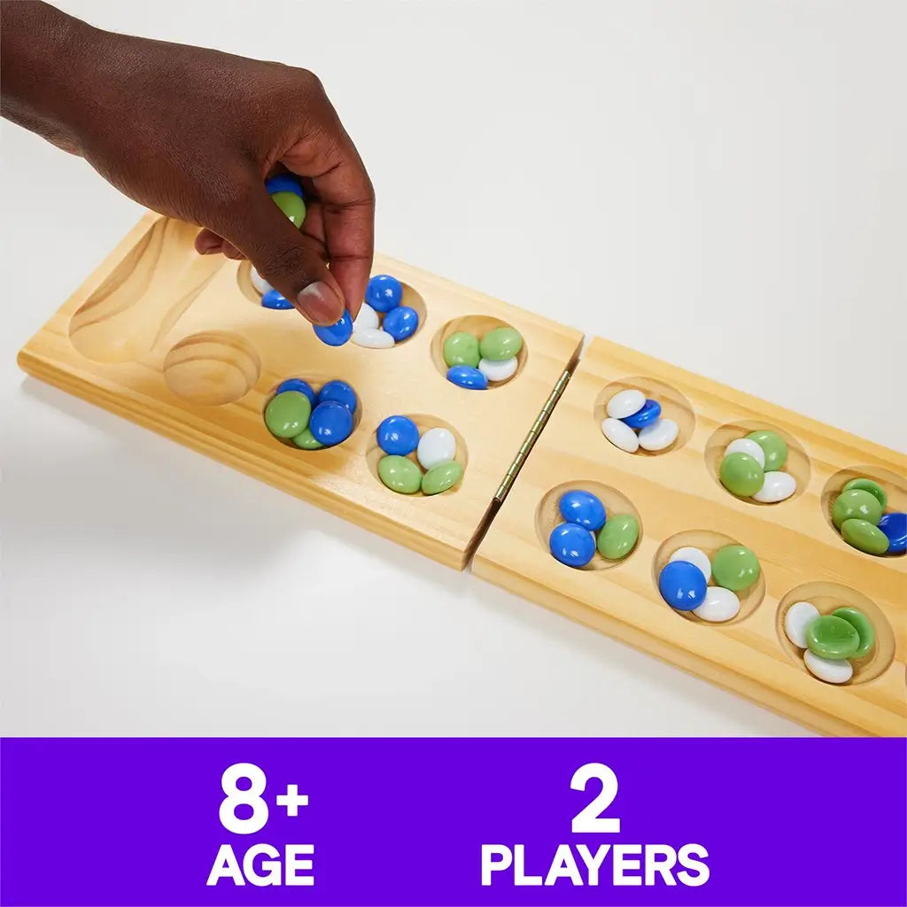 Close-up of a player’s hand placing colorful glass stones on a wooden Mancala board, shown with a caption noting it’s suitable for ages eight and up and two players.