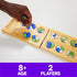 Close-up of a player’s hand placing colorful glass stones on a wooden Mancala board, shown with a caption noting it’s suitable for ages eight and up and two players.