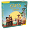 Catan Junior board game box features teal cardboard with large yellow title lettering and illustrated young pirates, a colorful parrot, goat, crates, and tropical island dock.