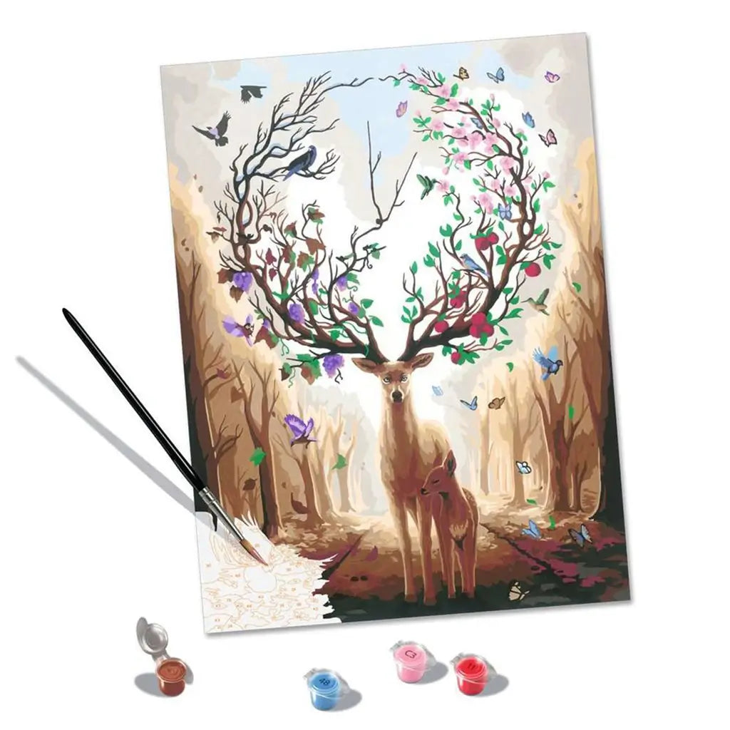 Paint by numbers set including a deer and fawn illustration with tree-branch antlers, three acrylic paint pots in primary shades, and a fine black brush displayed on a white background.