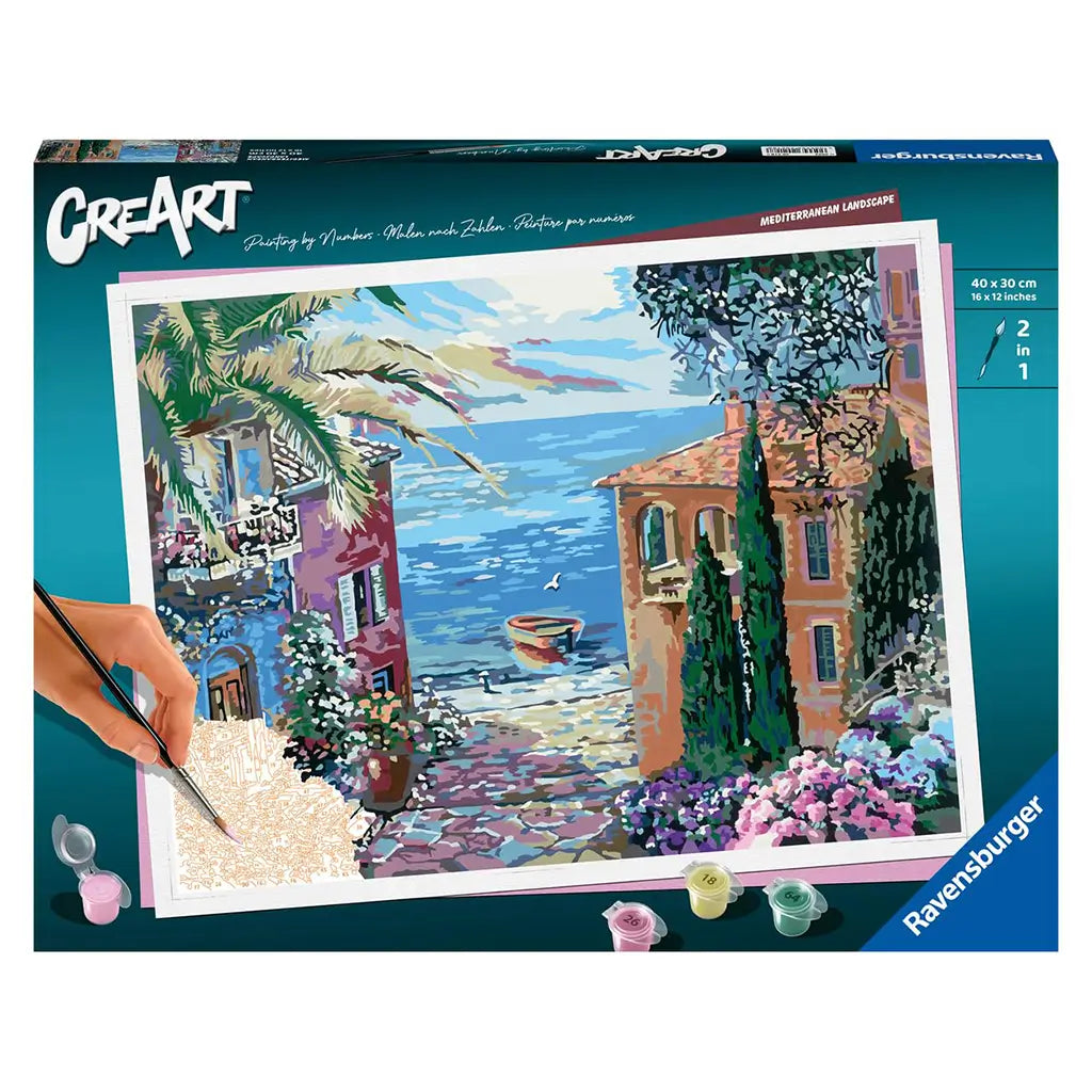 Ravensburger CreArt paint by numbers kit box featuring a Mediterranean landscape design with terracotta villas, blue sea, flowering plants, and a hand holding a brush painting details.