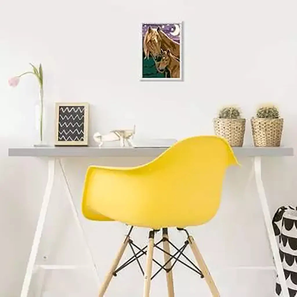 Finished CreArt “Horses at Midnight” artwork framed and hanging above a modern desk with yellow chair, showing how the painting fits into a home décor setting.
