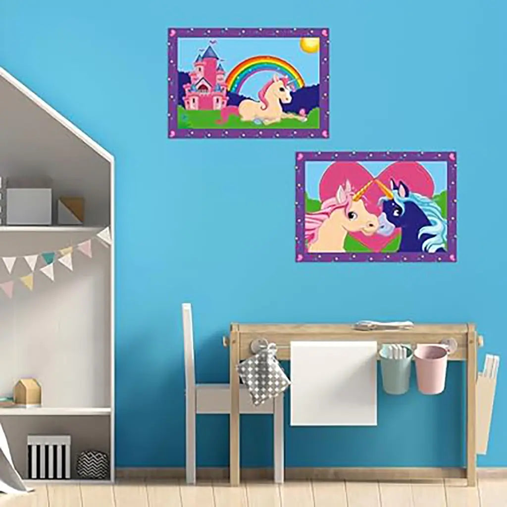 Children’s playroom with blue wall displays framed unicorn paintings, one with castle and rainbow and another with two unicorns in front of a heart, above a desk.