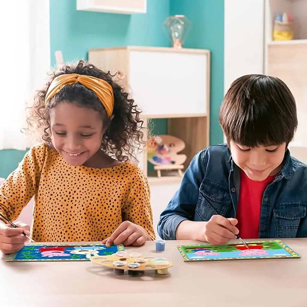 Two children happily painting Peppa Pig CreArt Jr numbered canvases at a table with brushes and included paint pots, encouraging creativity and fun.