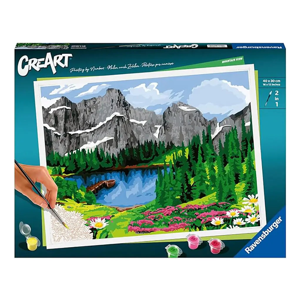 Ravensburger CreArt paint by numbers kit featuring a mountain view design with gray rocky peaks, blue sky, green forest, lake, and colorful flower meadow.