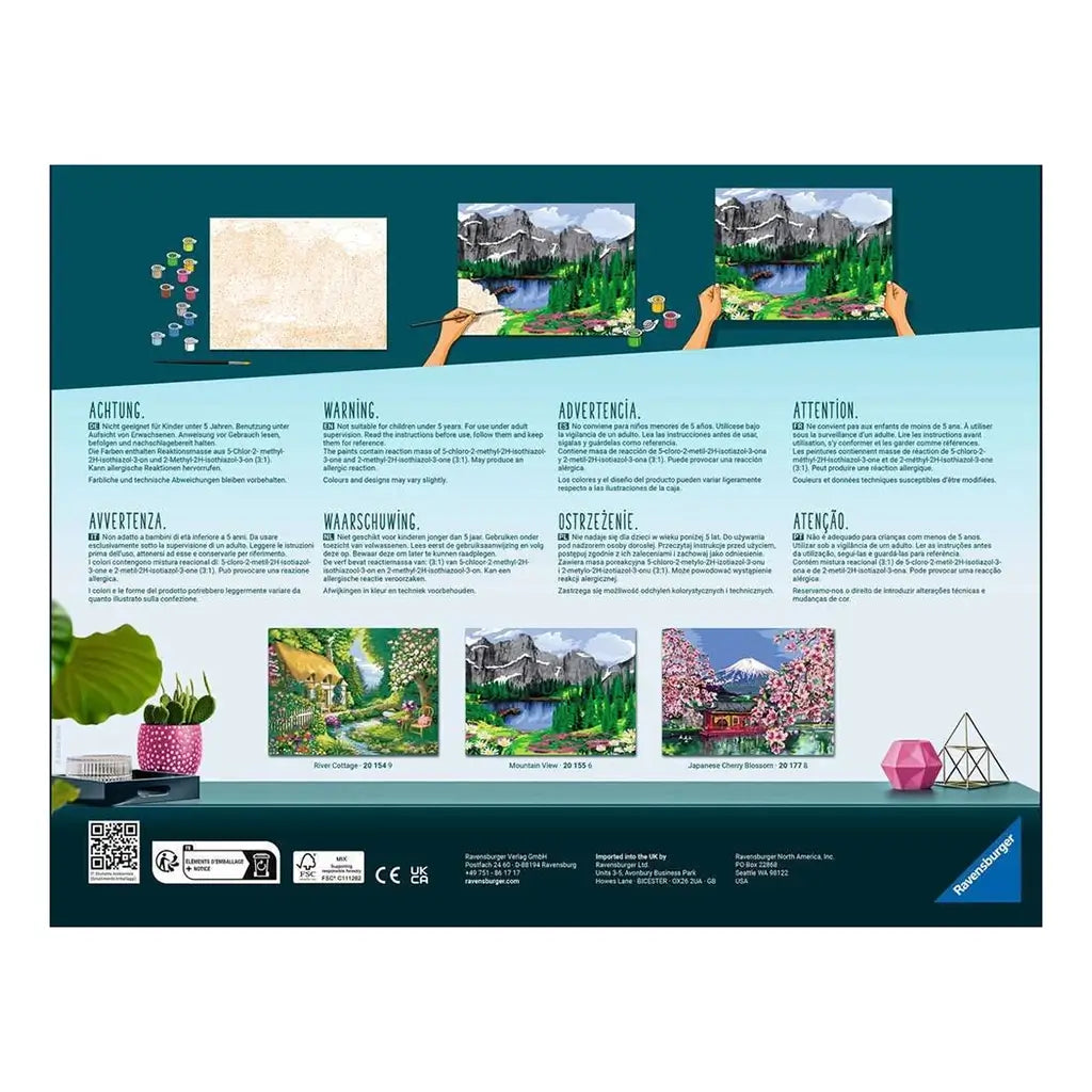 Back of Ravensburger CreArt River Cottage paint by numbers kit package showing instructions in multiple languages with preview images of other scenic painting options.