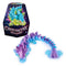 Articulated dragon toy in translucent purple and blue plastic with angular crystal scales, curved segmented body, and flared tail, posed beside Crystalynx Dragons mystery packaging on a white background.