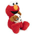 Side angled view of plush Elmo with shaggy red fur sitting cross-legged and holding small puppy Tango, showcasing embroidered paw swirl and cuddly design.