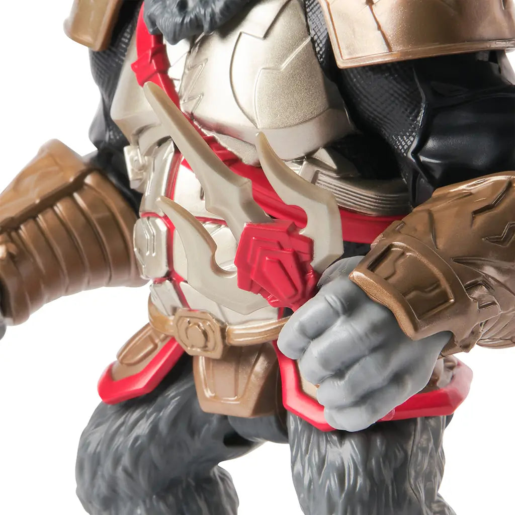 Detail shot of Gorilla Grodd figure’s chest armor with red sash and removable trident weapon, highlighting the sculpted textures and warrior-style design elements.