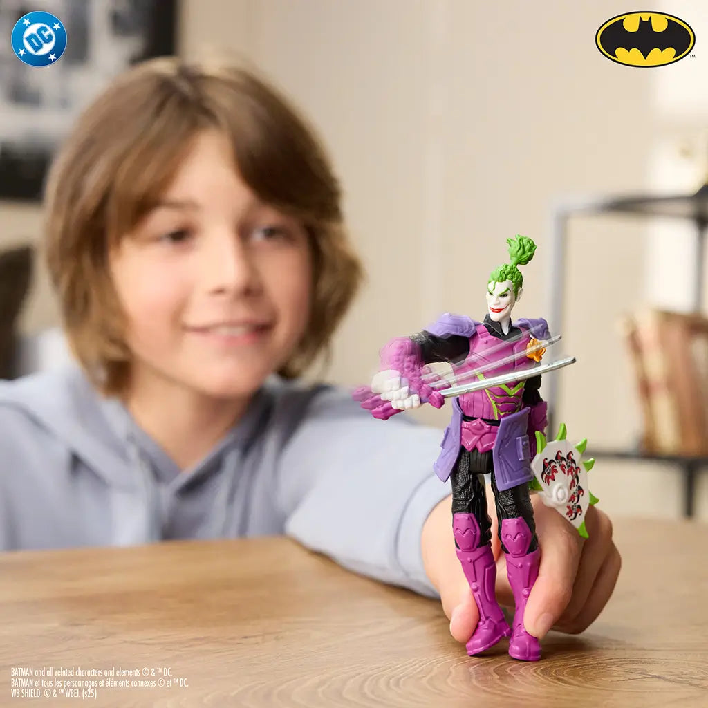 Boy demonstrating action movement of Ninja Strike The Joker 6-inch figure, with sword swinging pose and colorful spiked shield accessory in playful environment.